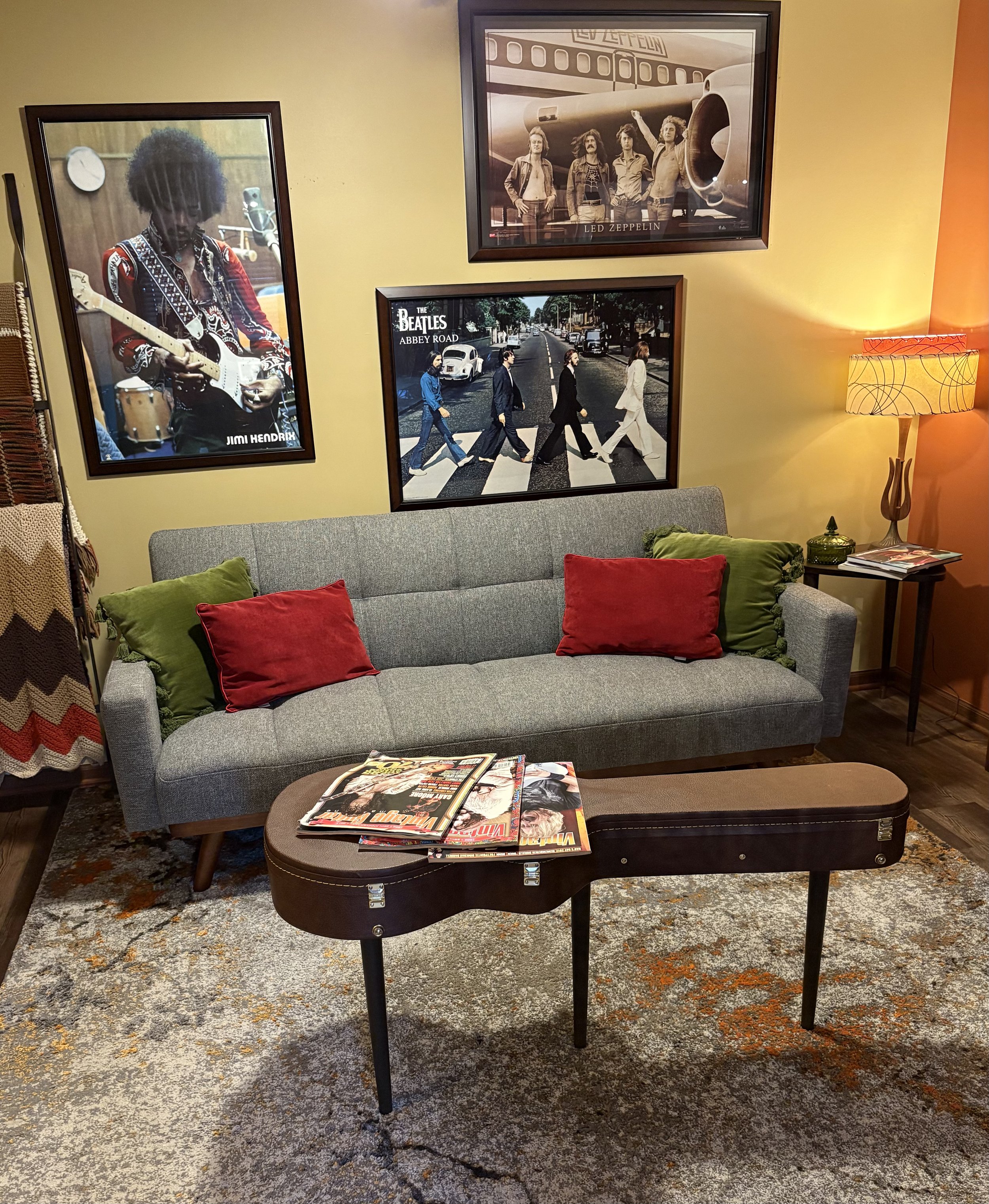Mid-century lounge corner with classic rock posters and a guitar-case coffee table